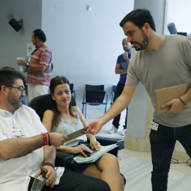 El coordinador federal de IU, Alberto Garzón, reparte invitaciones de su boda momentos antes de presentar a la asamblea federal de su formación el informe que hace balance sobre la alianza con Podemos y en el que reclama una mayor visibilidad frente al 