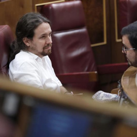 El secretario general de Podemos, Pablo Iglesias conversa con el coordinador general de IU, Alberto Garzón, durante el pleno del Congreso que se celebró el 20 de junio. | CHEMA MOYA (EFE)