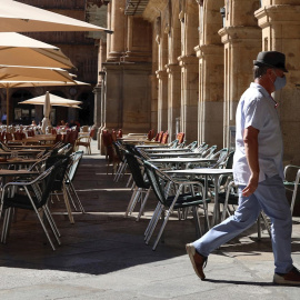 Un hombre con mascarilla pasa frente a una terraza de un restaurante de la plaza mayor de Salamanca, este miércoles. | EFE