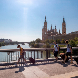 Varias personas con maletas cruzan el Puente de Santiago de Zaragoza. EFE/Javier Belver/Archivo