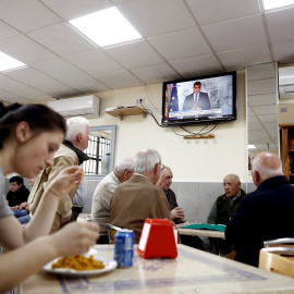 12/03/2020.- Un grupo de ancianos juega a las cartas este jueves en un bar del barrio de Aluche, en Madrid, mientras en la televisión comparece el presidente del Gobierno por el coronavirus. / EFE - MARISCAL