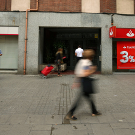 Varios personas pasan junto a sendas oficinas de Banco Popular y Banco Santander, en Barcelona. REUTERS/Albert Gea