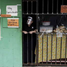 Una mujer con su careta puesta vende alimentos en la puerta de su casa hoy viernes 24 de julio, en San José, Costa Rica. EFE/Jeffrey Arguedas