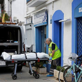 Un empleado de una funeraria saca el cadáver del hombre que ha fallecido al ser tiroteado cuando se encontraba en el bar de Vilanova i la Geltrú (Barcelona) donde trabajaba. | SUSSANA SÁEZ (EFE)