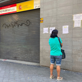 Una persona observa uno de los carteles con instrucciones para hacer trámites por internet colocados en la fachada de una oficina del SEPE. E.P./Eduardo Parra