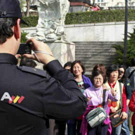 Un policía toma una foto a un grupo de turistas japoneses en Madrid.-EFE