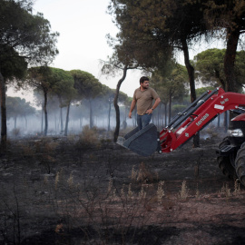 Un hombre se monta en un tractor mientras ayuda a apagar el incendio forestal cerca del Parque Nacional de Donaña en Mazagón. REUTERS/Jon Nazca