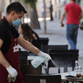 Un camarero desinfecta una mesa de una terraza / EFE