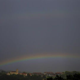 Vista de un arco iris sobre el cielo negro de San Sebastián, donde aún este viernes se mantiene la alerta amarilla por fenómenos costeros. | EFE