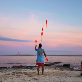 Una hombre realiza malabares al atardecer en la playa de Punta Prima en Menorca, Baleares, este miércoles. EFE/ David Arquimbau Sintes
