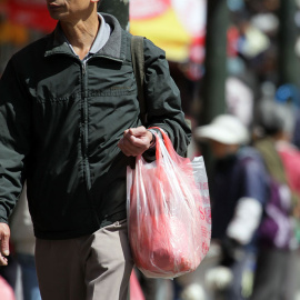 Un hombre carga una bolsa de plástico con la compra. AFP