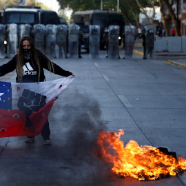 Una manifestante sostiene un a bandera de Chile frente a un contingente de Fuerzas Especiales de Carabineros durante una protesta en la Plaza Italia de Santiago. EFE/Alberto Valdés