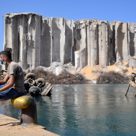 Un hombre permanece sentado en el puerto de Beirut junto a la zona de la gran explosión del 4 de agosto. - EFE