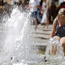 Una turista se refresca en la fuente de la plaza de la Virgen de Valencia. /EFE