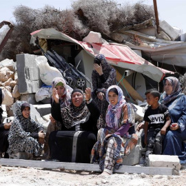 17/06/2019.- Una familia palestina permanece sentada cerca de los escombros de su casa tras ser demolida por las fuerzas israelíes, este lunes, en Yatta, al sur de Hebrón. El ejército israelí destruye las casas de aquellos palestinos que no tienen los