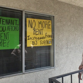 El mariachi mexicano Luis Valdivia posa frente dos carteles que denuncian la escalada del alquiler con la llegada de nuevo propietario. Crédito: Aitana Vargas (4/8/2017)
