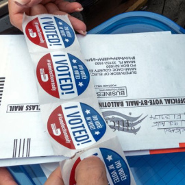 Una persona distribuye unas pegatinas que dicen "Yo voté", que se entregan a las personas tras votar en la puerta de un centro de votación en Miami, Florida (EEUU). EFE/Giorgio Viera/Archivo