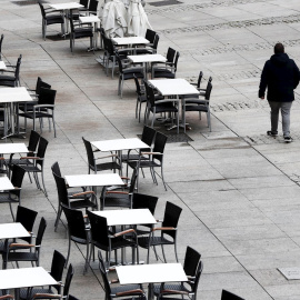 22/10/2020.- Dos personas caminan por la Plaza del Castillo de Pamplona que hoy jueves presenta un inusual aspecto con las terrazas de los bares vacías en una jornada en la que cientos de pamploneses salen este día "Juevintxo", para compartir en la call