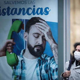 26/10/2020.- Una mujer pasa junto a un panel publicitario este lunes en San Sebastián. El alcalde donostiarra, Eneko Goia, ha informado hoy de que la ciudad ha entrado en "zona roja" y se prepara para adoptar las restricciones impuestas a los municipios 