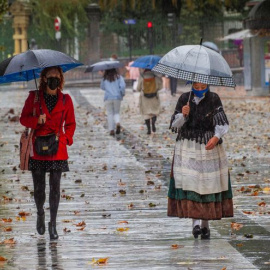 Dos mujeres pasean bajo la lluvia en el paseo de Los Álamos, en el centro de Oviedo, Asturias. EFE/Alberto Morante