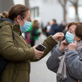 Una mujer ayuda a otra a colocarse la mascarilla este martes en Barcelona.