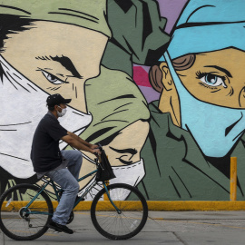 Un hombre pasa en bicicleta frente a un mural en Ciudad Juárez.