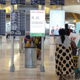 Pasajeros cerca de páneles informativos en la terminal T4 del aeropuerto Adolfo Suárez Madrid-Barajas. E.P./Jesús Hellín