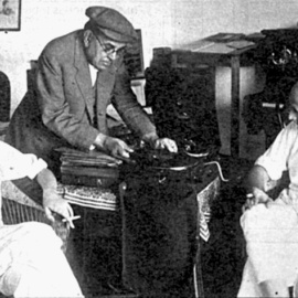 Planes (esquerra) i Sagarra (dreta) en companyia del mestre Vives, que posa un disc en una gramola (Font desconeguda).