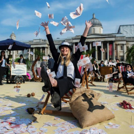 Una mujer lanza billetes al aire en una protesta contra los paraísos fiscales en la plaza Trafalgar de Londres. EFE/Hannah Mckay