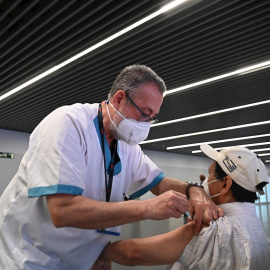 Un sanitario vacuna a una persona en el estadio Wanda Metropolitano en Madrid, que acoge este martes el inicio de la vacunación con Astrazeneca para la población general de 60 a 65 años, que toman el relevo de los mayores de 80 años que viven en sus d
