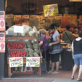 Varias personas compran en una frutería.