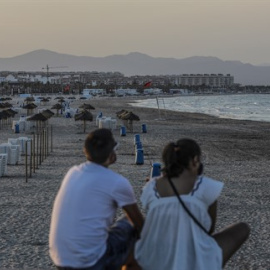 Dos jóvenes sentados contemplan la playa de la Malvarrosa durante la noche de San Juan en Valencia, Comunidad Valenciana (España), a 23 de junio de 2020.