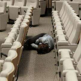 Una periodista duerme en el suelo de la sala de prensa de la sede de la Comisión Europea en Bruselas, mientras espera el final de la cumbre. (YVES HERMAN | REUTERS)