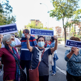 Tres mujeres muestran pancartas en las que figura una placa para la Calle Maestra Justa Freire, en una manifestación para que su nombre vuelva a la que hoy es la calle General Millán-Astray.