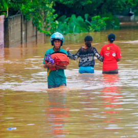 04/04/2021. Un hombre con casco lleva consigo sus pertenencias en un área afectada por las fuertes inundaciones en Indonesia y Timor Oriental. - Reuters