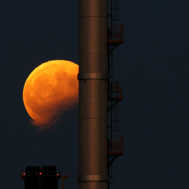 Imagen del eclipse lunar detrás de las chimeneas de una central eléctrica en Delimara (Malta). Darrin Zammit / REUTERS