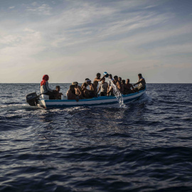 Un grupo de 17 jóvenes tunecinos achican agua de la patera en la que navegan hacia Lampedusa (Italia) escoltadas por el buque Astral de Open Arms, este miércoles.