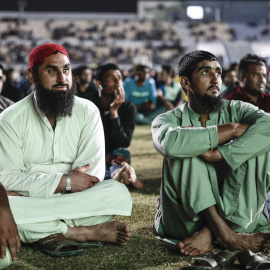 Trabajadores migrantes siguen uno de los partidos del Mundial de Catar desde uno de los campamentos, a las afueras de la capital.