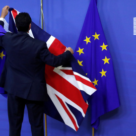 Un empleado de la Comisión Europea coloca las banderas de la UE y del Reino Unido en la sede de institución comunitaria con motivo de la primera reunión para la negociación del Brexit, el pasado 17 de julio, en Bruselas. REUTERS/Yves Herman