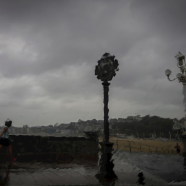 Una mujer camina bajo la lluvia en San Sebastián.