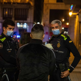 Una pareja de la Guardia Urbana multa a una persona tras la entrada en vigor del toque de queda, a 24 de diciembre de 2021, en Barcelona, Catalunya (España).