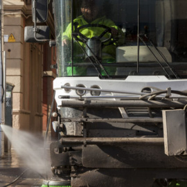 Un trabajador de la limpieza utiliza agua a presión para limpiar las aceras.