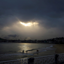 Varias personas en la playa de Ondarreta de San Sebastián, donde los cielos de Euskadi se presentan nubosos y con chubascos.