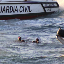 Miembros del Grupo Especial de Actividades Subacuáticas (GEAS) de la Guardia Civil sacan del agua el cuerpo de un inmigrante subsahariano que ha fallecido ahogado tras ser abandonado, junto a otros once inmigrantes, por seis motos de agua que los transpo