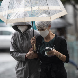 Dos personas se protegen de la lluvia bajo un paraguas, en Sevilla.