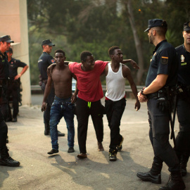 Agentes de la Guardia Civil junto a tres de los migrantes tras cruzar la frontera. REUTERS