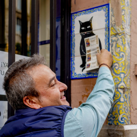 Una persona pone el décimo recién comprado en el azulejo que representa a el gato negro en la administración de loterías ‘El Gato Negro’ en Sevilla- 07/12/2022