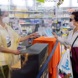 Una empleada de farmacia entrega de forma gratuita dos mascarillas a una pensionista mediante la receta electrónica. /EFE