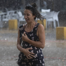 Una mujer corre bajo la lluvia en la Alameda de Hércules (Sevilla) a 14 de septiembre de 2021.