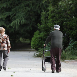 Una mujer y un hombre de edad avanzada con andador paseando. En Madrid, (España).
